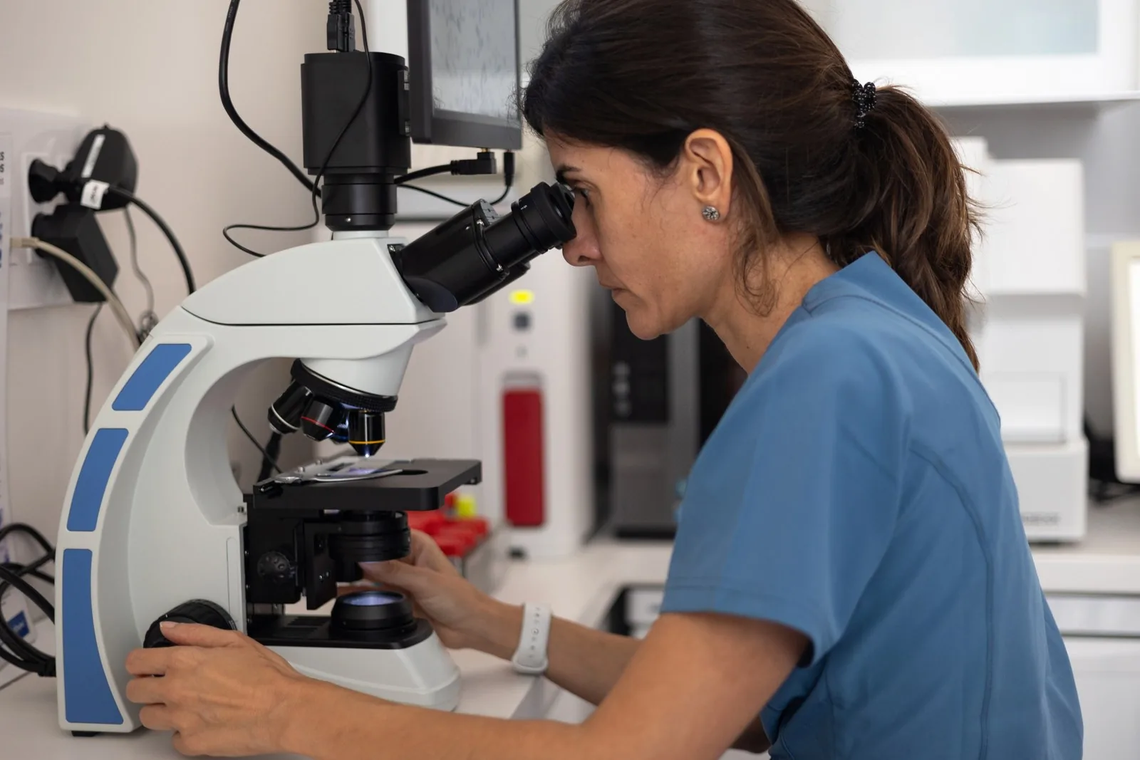 Veterinary technician examining samples through a microscope in the in-house laboratory